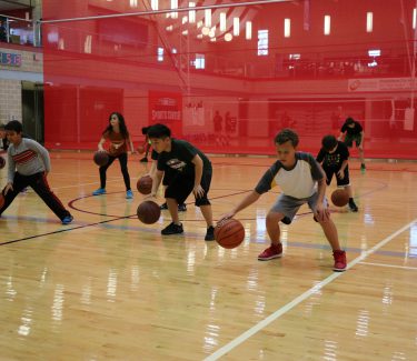 Kids dribbling basketball on court