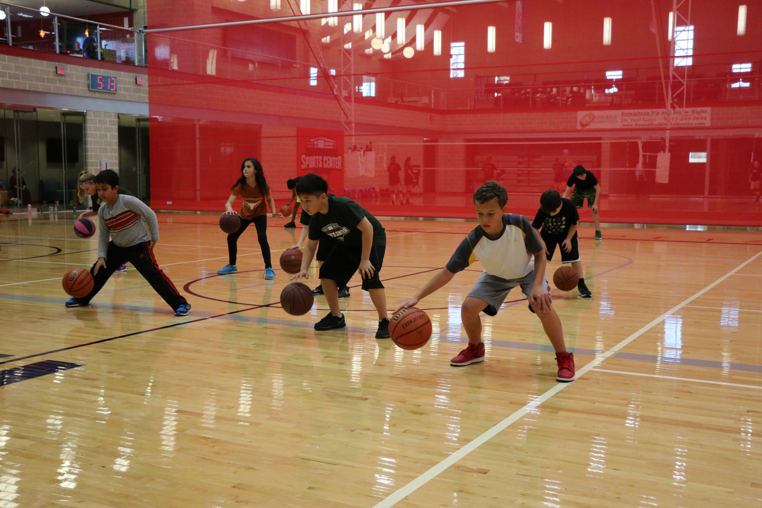 Kids dribbling basketball on court