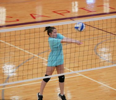 girl hitting volleyball on court