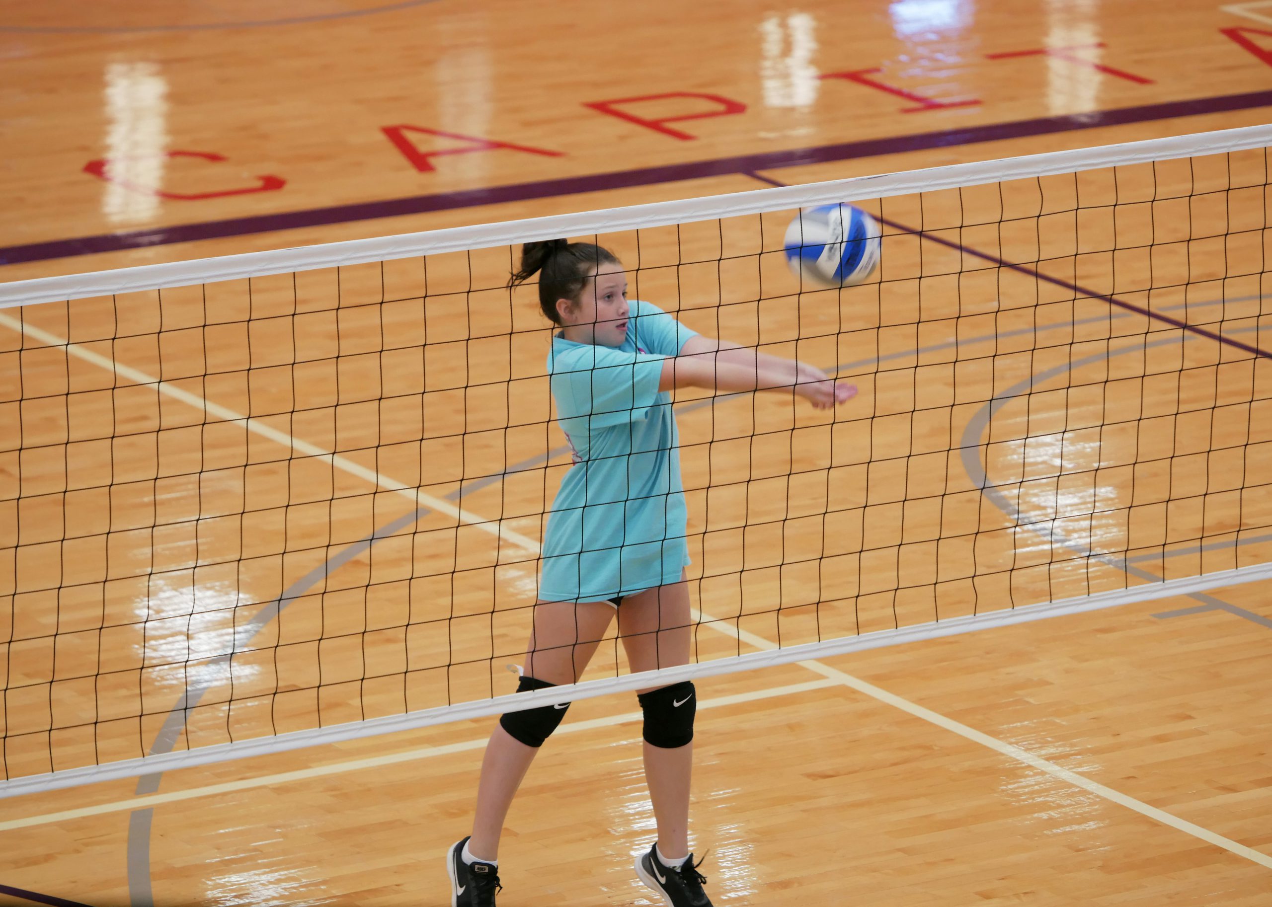 girl hitting volleyball on court