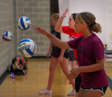 Girls bouncing volleyballs