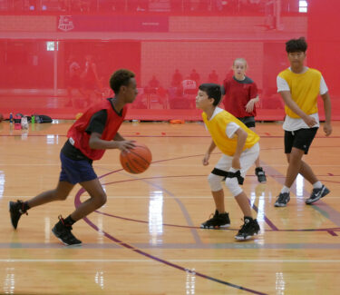 Teens playing basketball on court