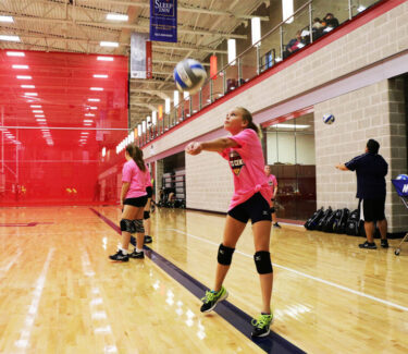 girl hitting volleyball on court