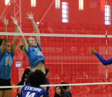 Volleyball players at net spiking